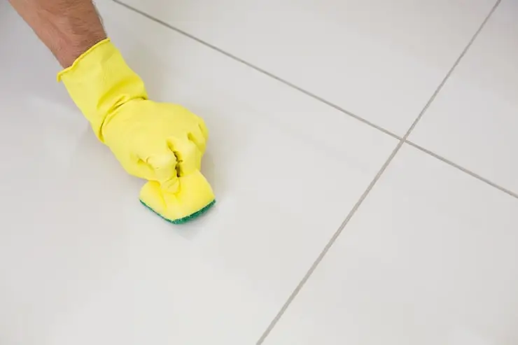yellow-gloved-hand-with-sponge-cleaning-floor_13339-36456